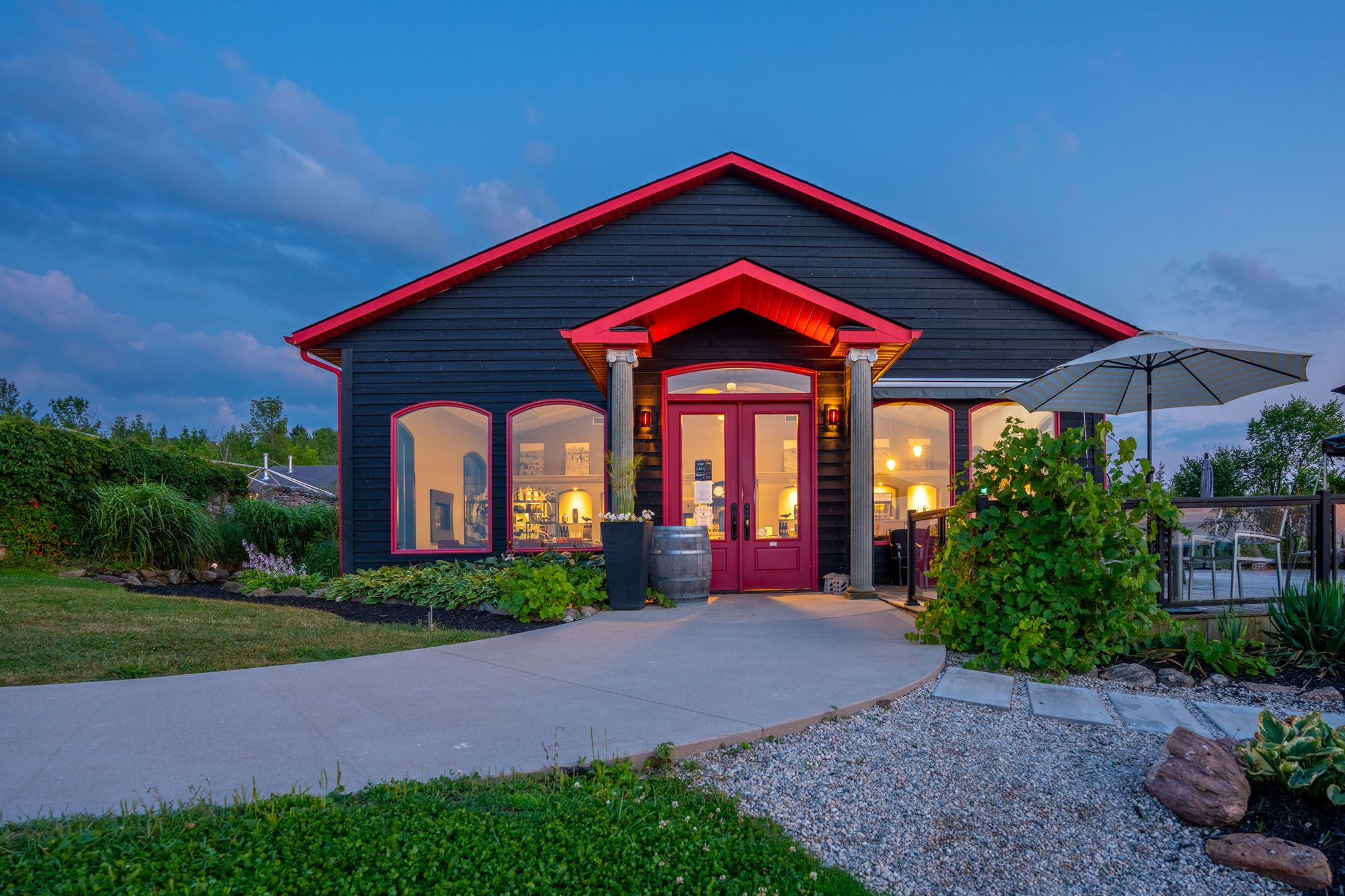 The tasting room lit up at dusk, its red doors and arched windows glowing